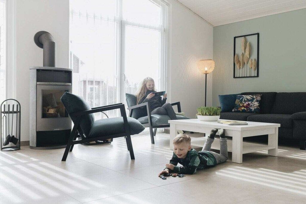 Un salon avec une cheminée, un canapé, une table basse et un enfant qui joue sur le sol.