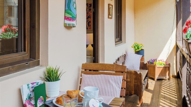 Un espace extérieur ensoleillé, aménagé avec des tables où l’on peut prendre le petit-déjeuner, avec des croissants et des boissons.