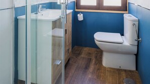 Une salle de bain avec une douche à parois de verre, un lavabo blanc, des toilettes et une fenêtre avec des cadres en bois.