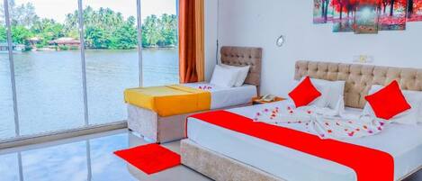 A hotel room with a large window, a bed, a sofa, and a painting on the wall.