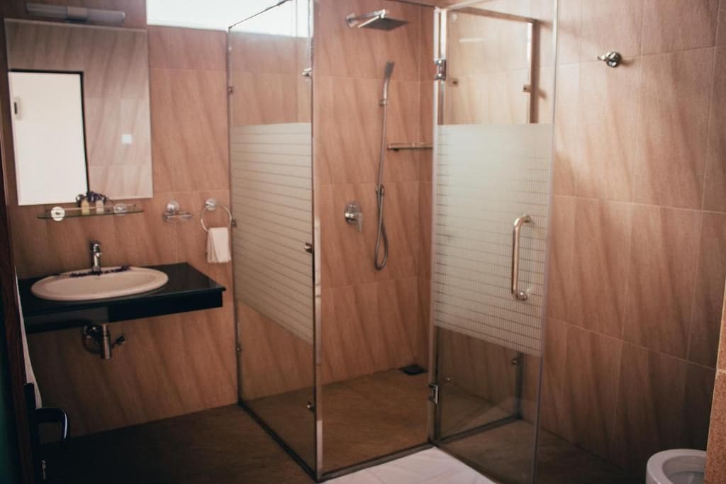 A modern bathroom with a glass-enclosed shower, a sink with a mirror above it, and a toilet.
