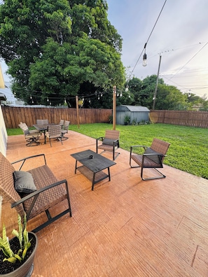 An outdoor patio with a wooden deck, wicker furniture, and a potted plant. - Spacious 4-bedroom house in peaceful Delray Beach minutes from Atlantic Ave! (Delray Beach)
