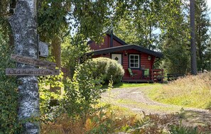 A cabin with a porch, surrounded by trees and a signpost indicating directions to 'Gotes Cabin' and 'Old Hunter's Cabin'. - 2 bedroom lovely home in årjäng (Årjäng)