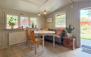 A cozy kitchen with wooden chairs, a round table, and a bench. There are windows with plants and a view of the outside. - 2 bedroom lovely home in årjäng (Årjäng)