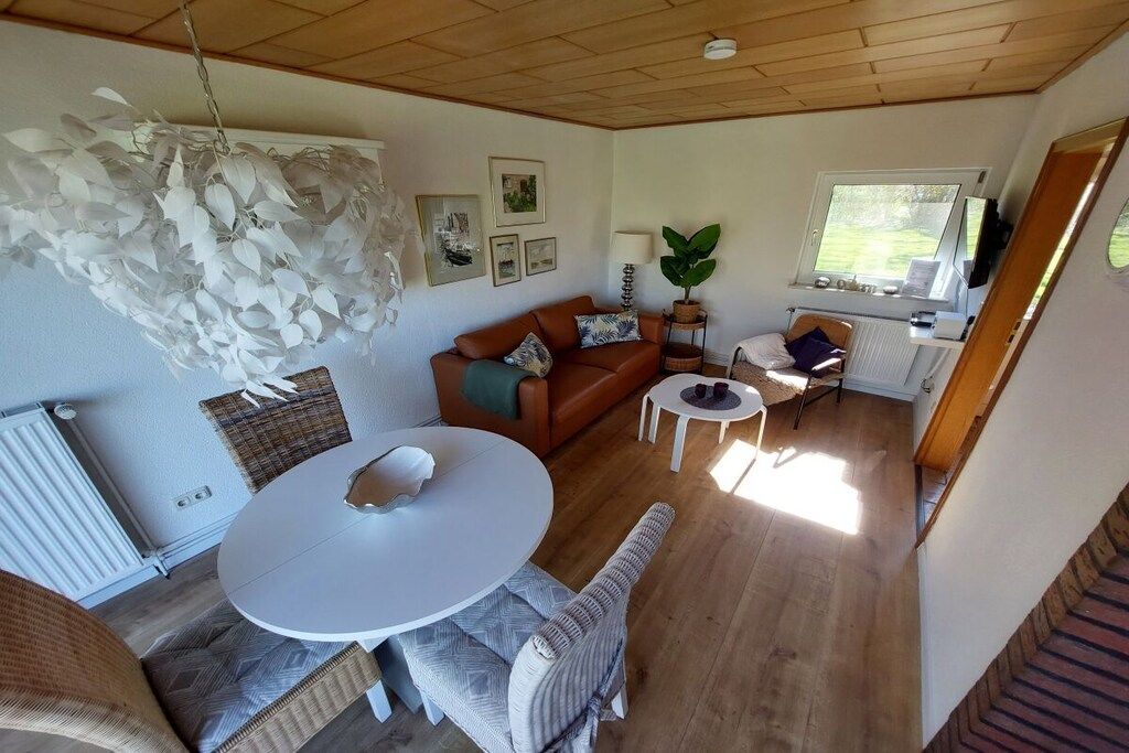 Et hyggeligt opholdsrum med et rundt bord, en sofa og en hængende lampe.