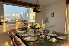 A dining area with a table set for four, a hanging light fixture, and a view of buildings through a window. - Houseboat in Olpenitz with swimming pool (Olpenitz)