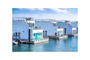 A waterfront property with multiple docked boats, a clear sky, and a calm water body. - Houseboat in Olpenitz with swimming pool (Olpenitz)