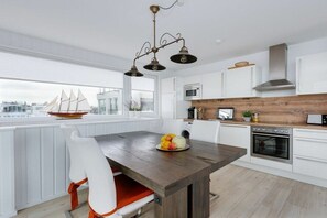 Een moderne keuken met witte kasten, een houten aanrecht en een eethoek met een tafel en stoelen.