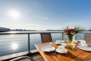 A table set for dining with a view of the water and city skyline. - Houseboat in Kappeln with swimming pool (Kappeln)
