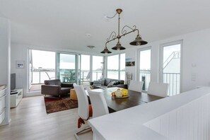 A modern kitchen with a dining area, large windows, and a view of the outdoors.