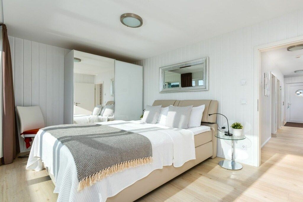 A modern bedroom with a bed, bedside table, and a mirror.