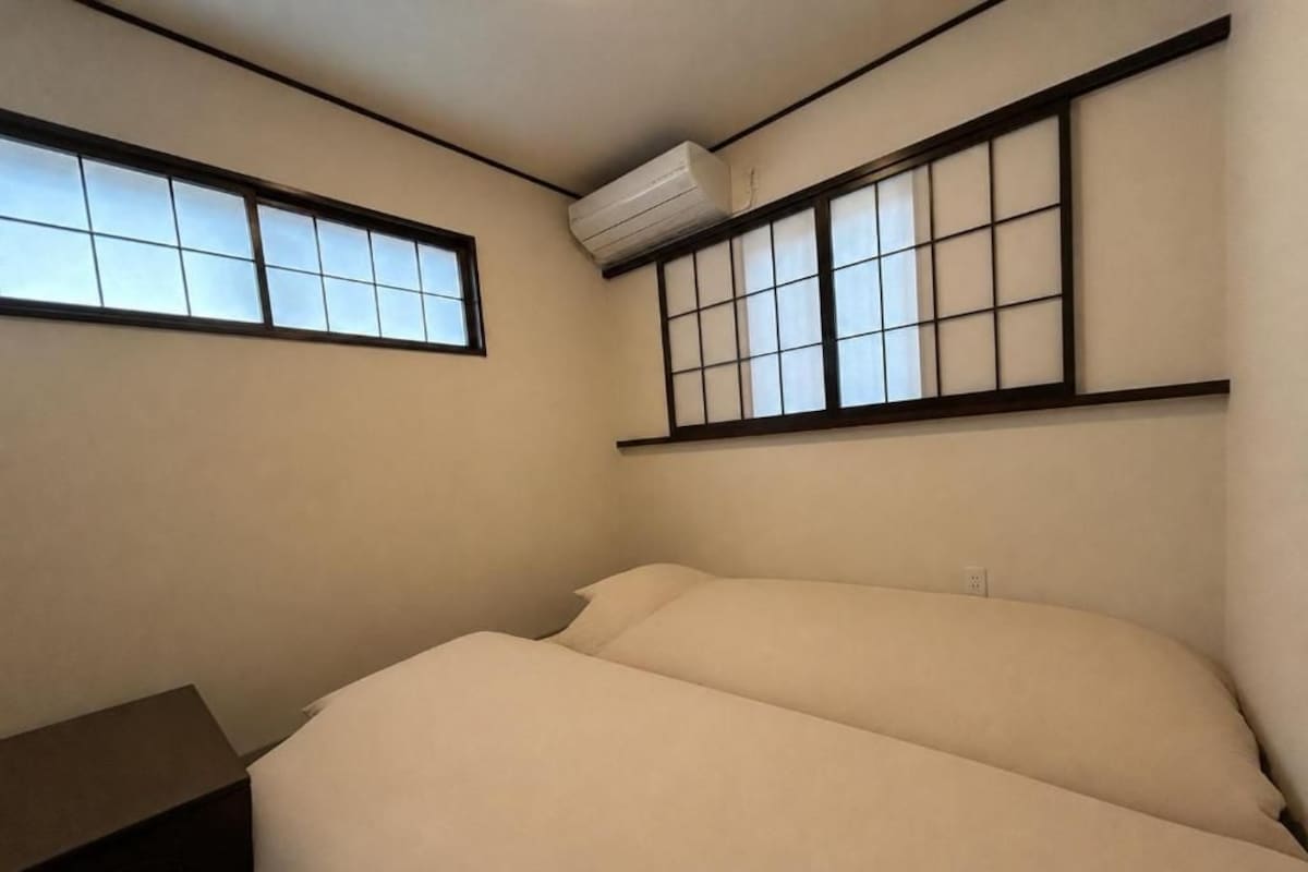Una habitación con una cama, una mesita de noche y un ventanal con vistas.