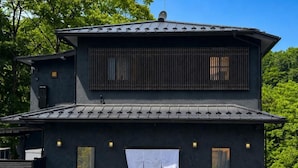 Ein Gebäude mit dunkler Fassade, einem Ziegeldach und einem Schild, das anzeigt, dass es sich um das River View Suites Hotel handelt.