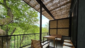 Ein Balkon mit Blick auf Bäume, einem Holztisch und einer Bank.