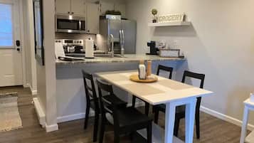 Una cocina moderna con zona de comedor, que incluye un microondas, refrigerador y un letrero en la pared que dice 'GROCERY'.