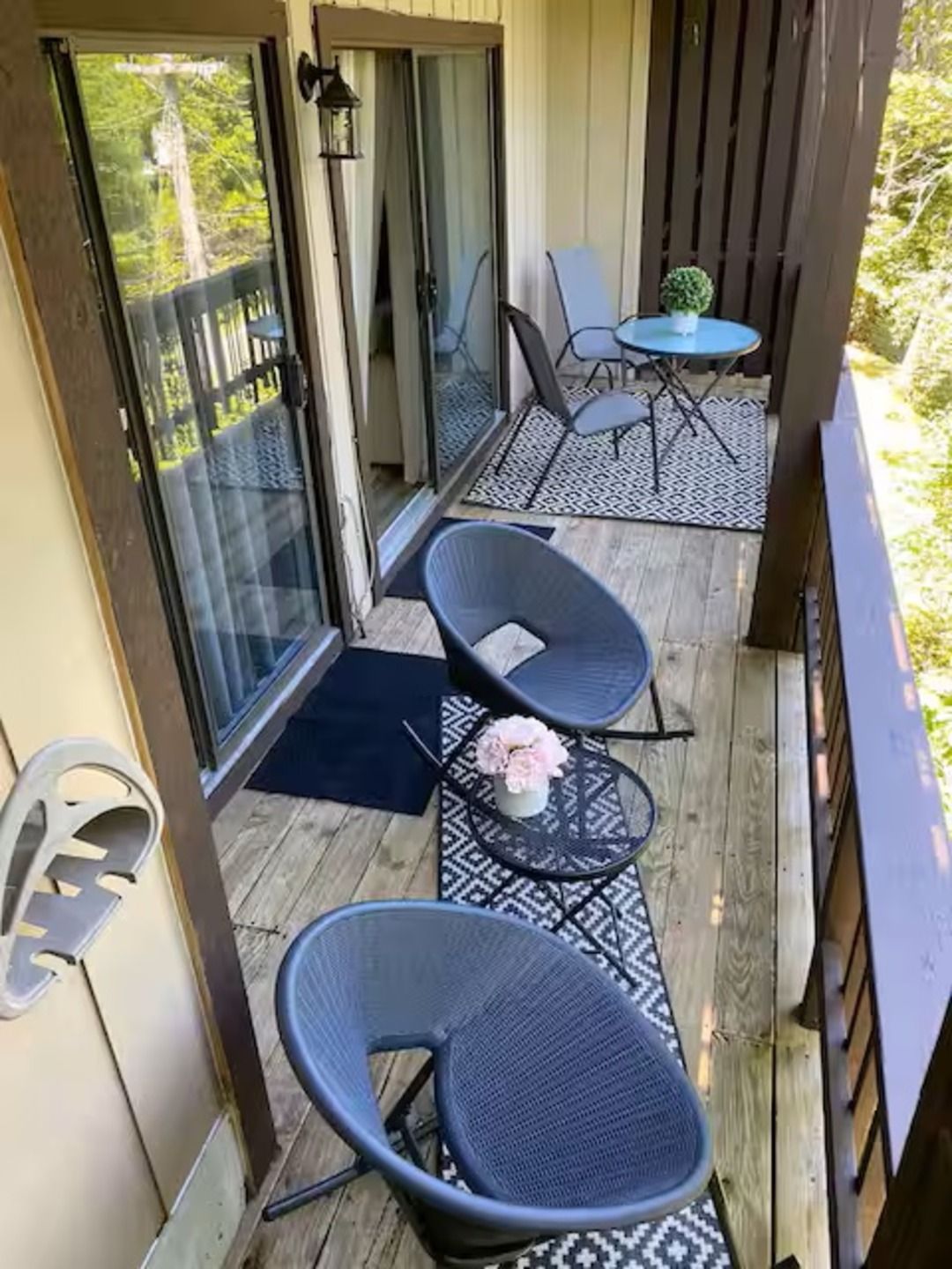 Un balcon avec deux chaises, une petite table et un pot de fleurs.