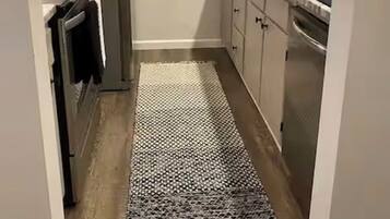 A narrow kitchen with a refrigerator, cabinets, and a sink.