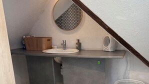 Un bany modern amb un rentapins integrat, un armari de fusta i un mirall rodó.
