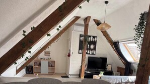 Habitació d'estil loft moderna amb zona de dinar, televisió i un llit amb altell.