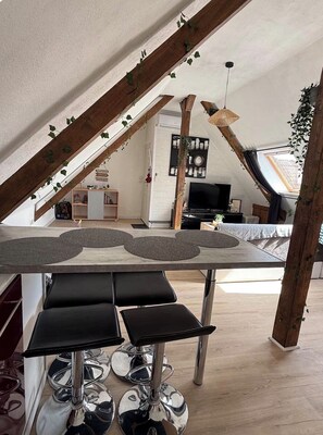 Ein modernes Loft mit Essbereich, Fernseher und einer erhöhten Schlafplattform.