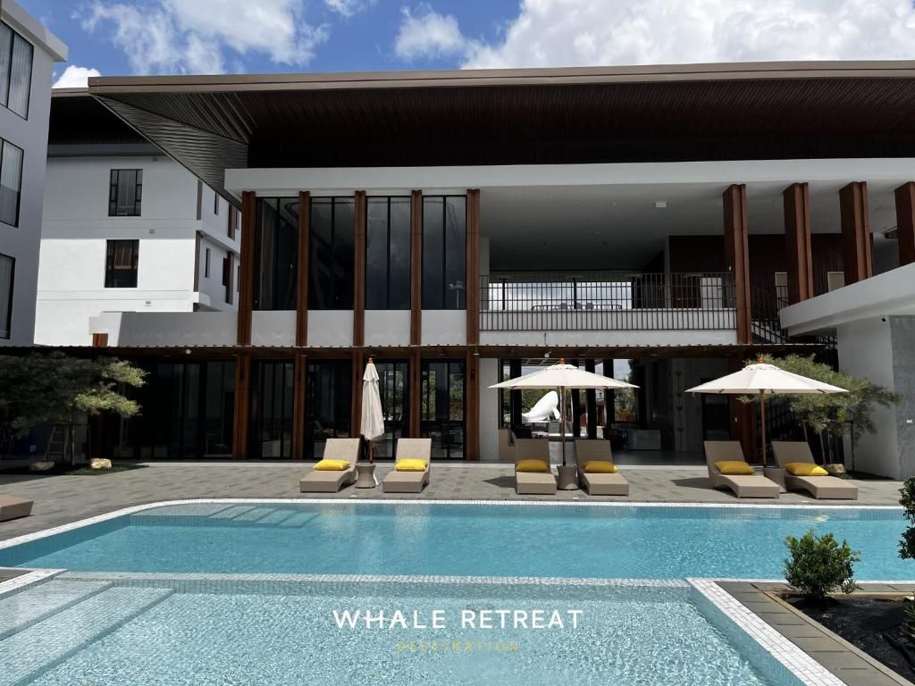 A modern building with a pool area, lounge chairs, and umbrellas.