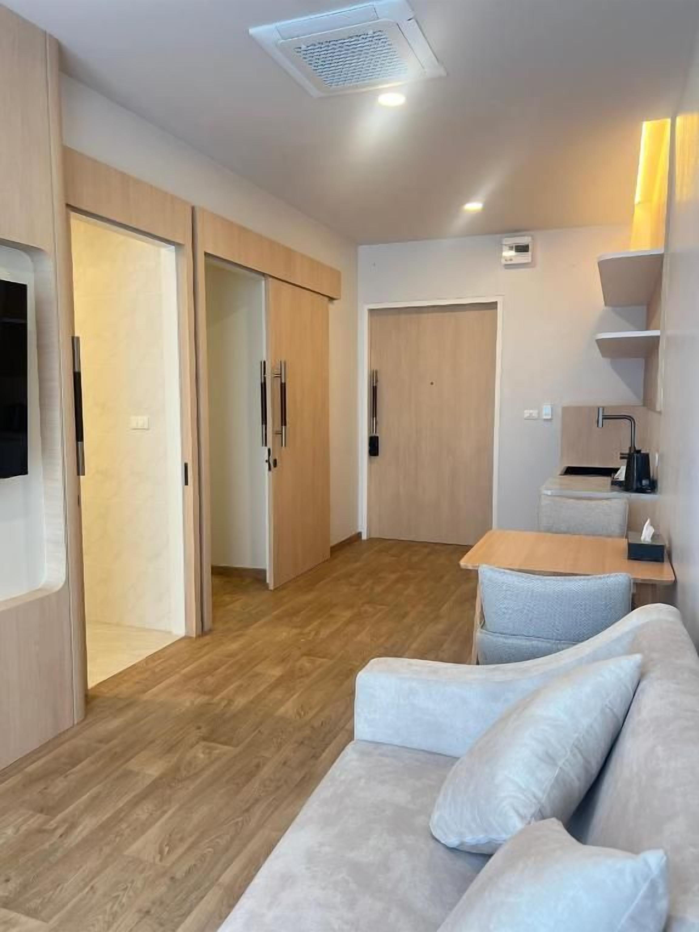 A modern living room with a sofa, a coffee table, and a small kitchen area with a sink and countertop.