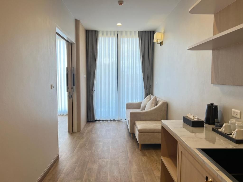 A hotel room with a sofa, a coffee machine, and a small table.