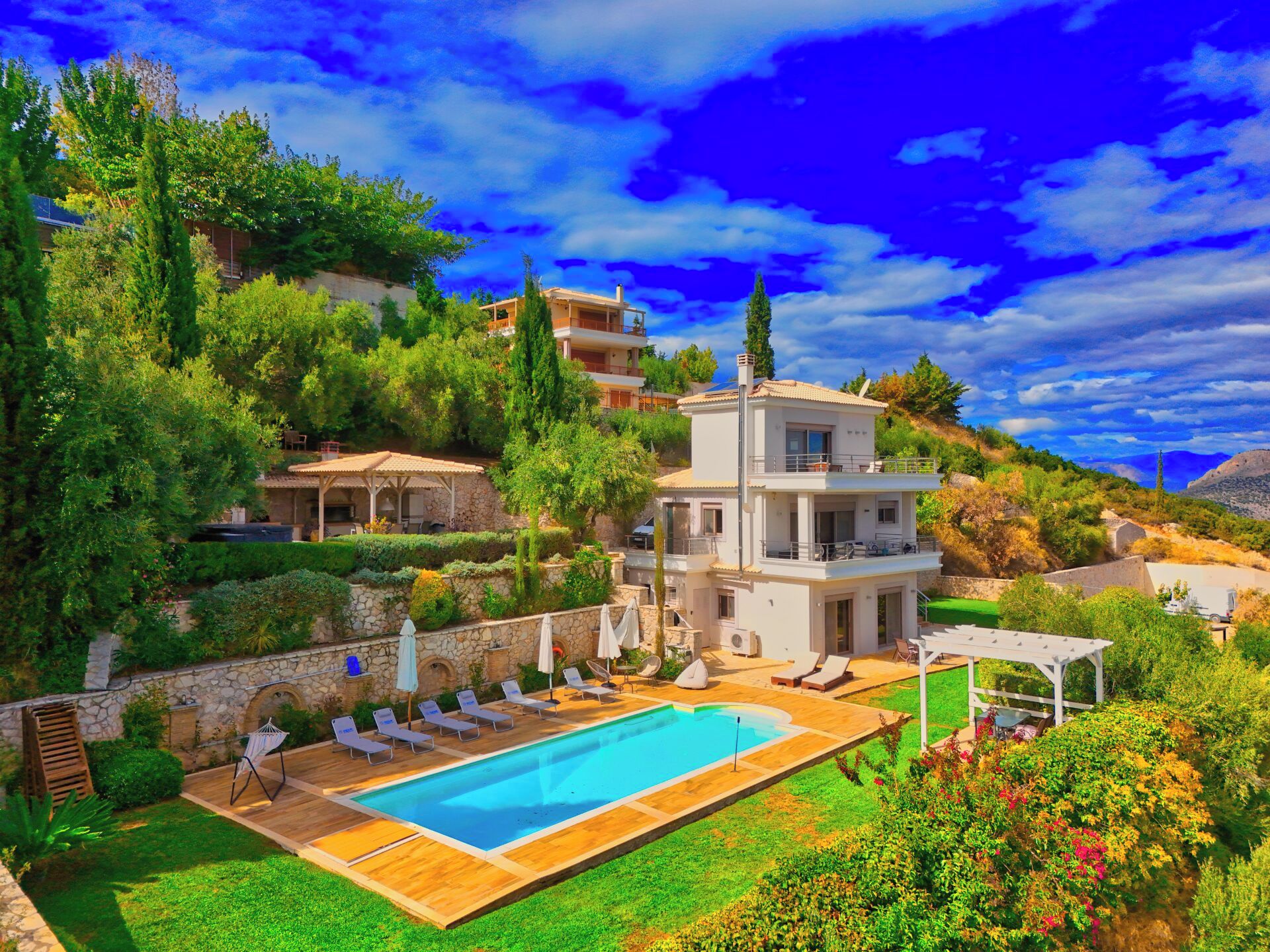 A modern villa with a swimming pool, multiple balconies, and lush greenery.