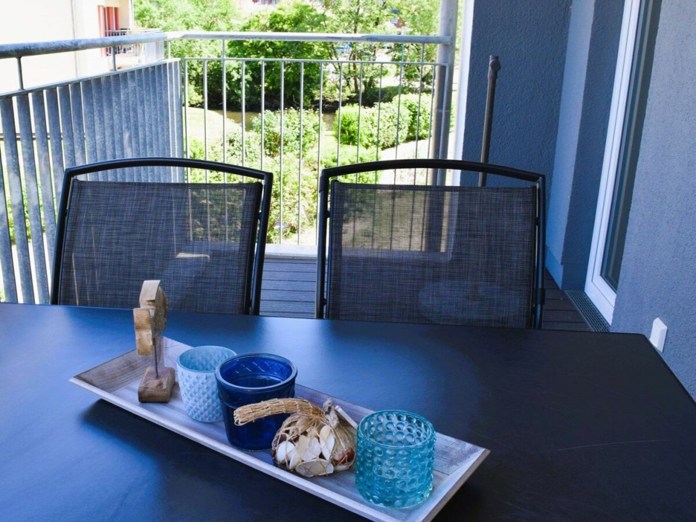 A balcony with two chairs, a table, and a tray with decorative items.
