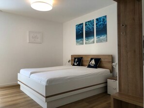 A modern bedroom with a bed, a bedside table, and a nightstand. There are three wall-mounted artworks above the bed. - 50.1.n North Bunk (Wangerland)