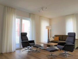 A modern living room with a sofa, two armchairs, a coffee table, and a floor lamp.
