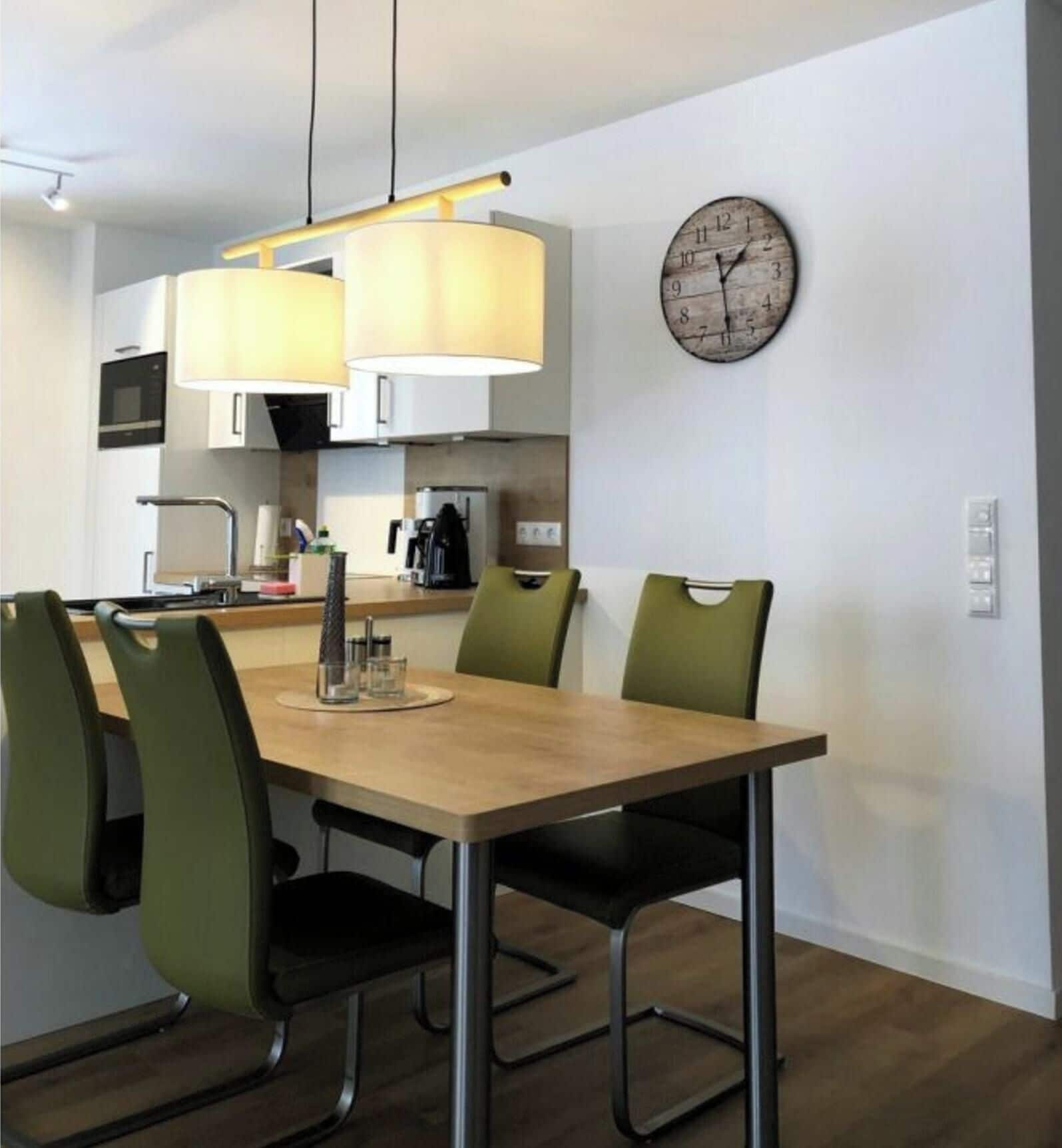 Una cocina moderna con una mesa de comedor, sillas y un reloj en la pared.
