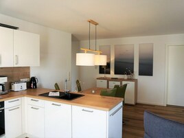 A modern kitchen with white cabinets, a wooden countertop, and a built-in dishwasher.