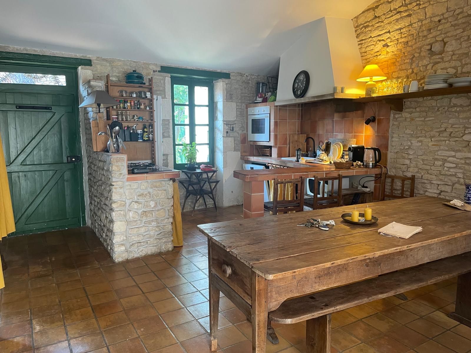 A rustic kitchen with a stone wall, wooden counter, and a dining table with chairs.