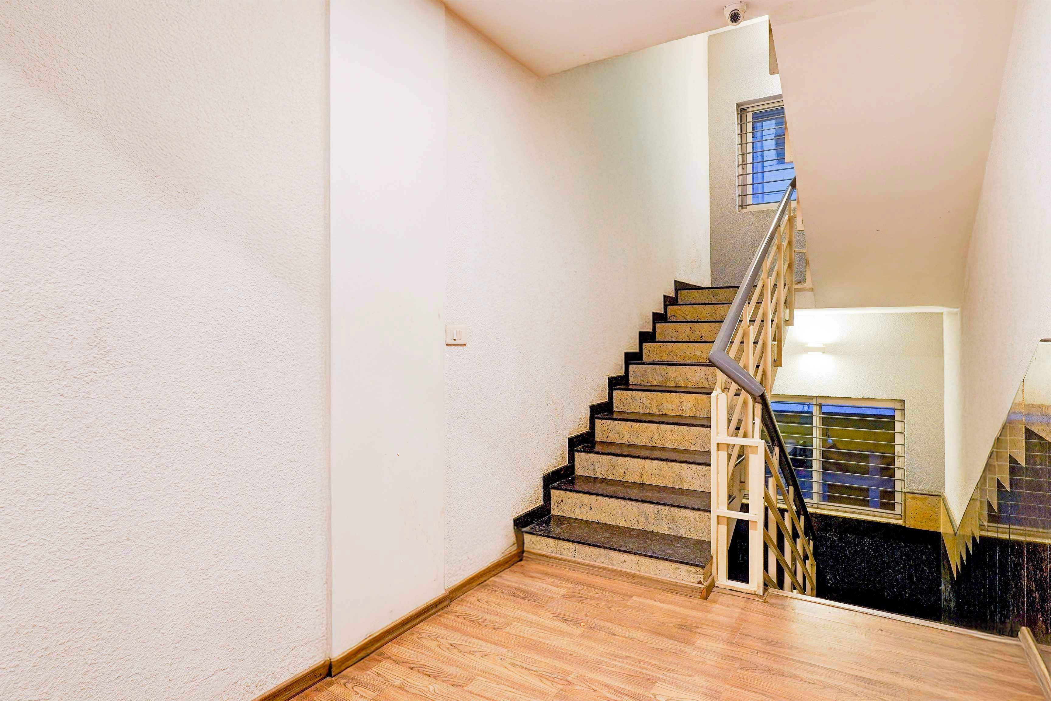 A staircase with a wooden handrail and a metal railing, leading to a landing with a window.
