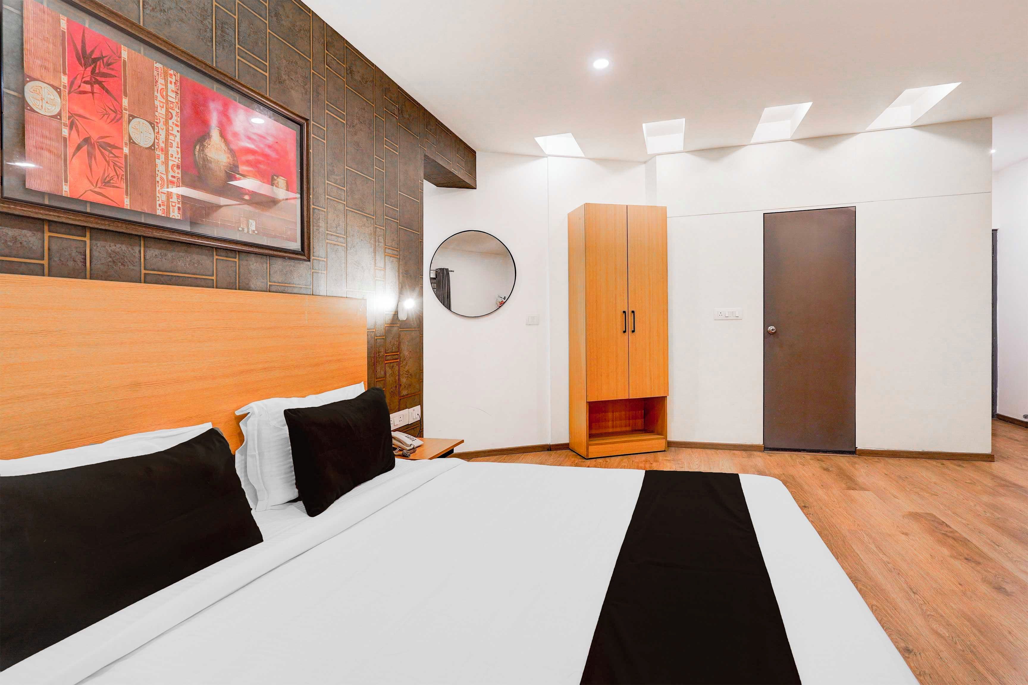 Quarto moderno com cama grande, guarda-roupa, espelho e uma obra de arte na parede.