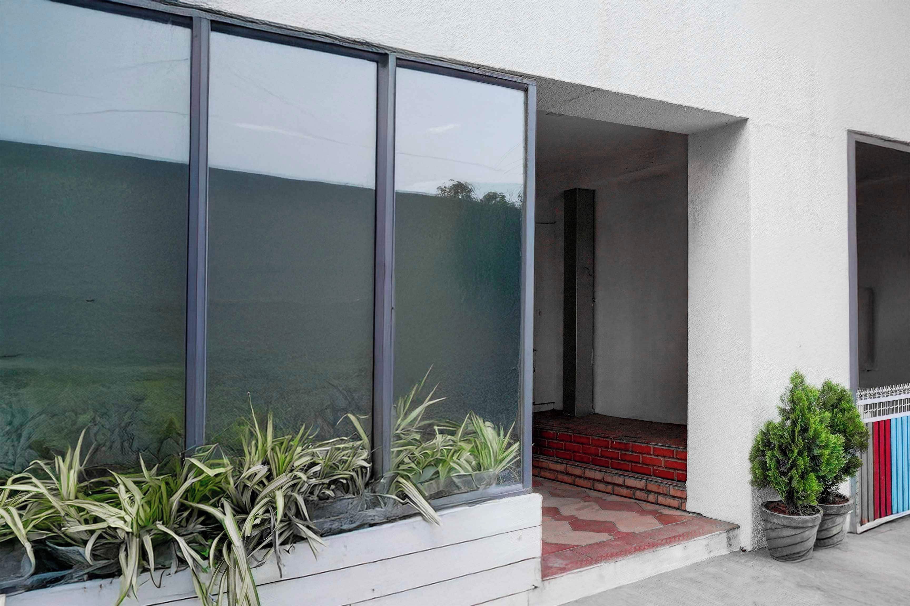 A modern building with large windows, a red brick entrance, and potted plants.