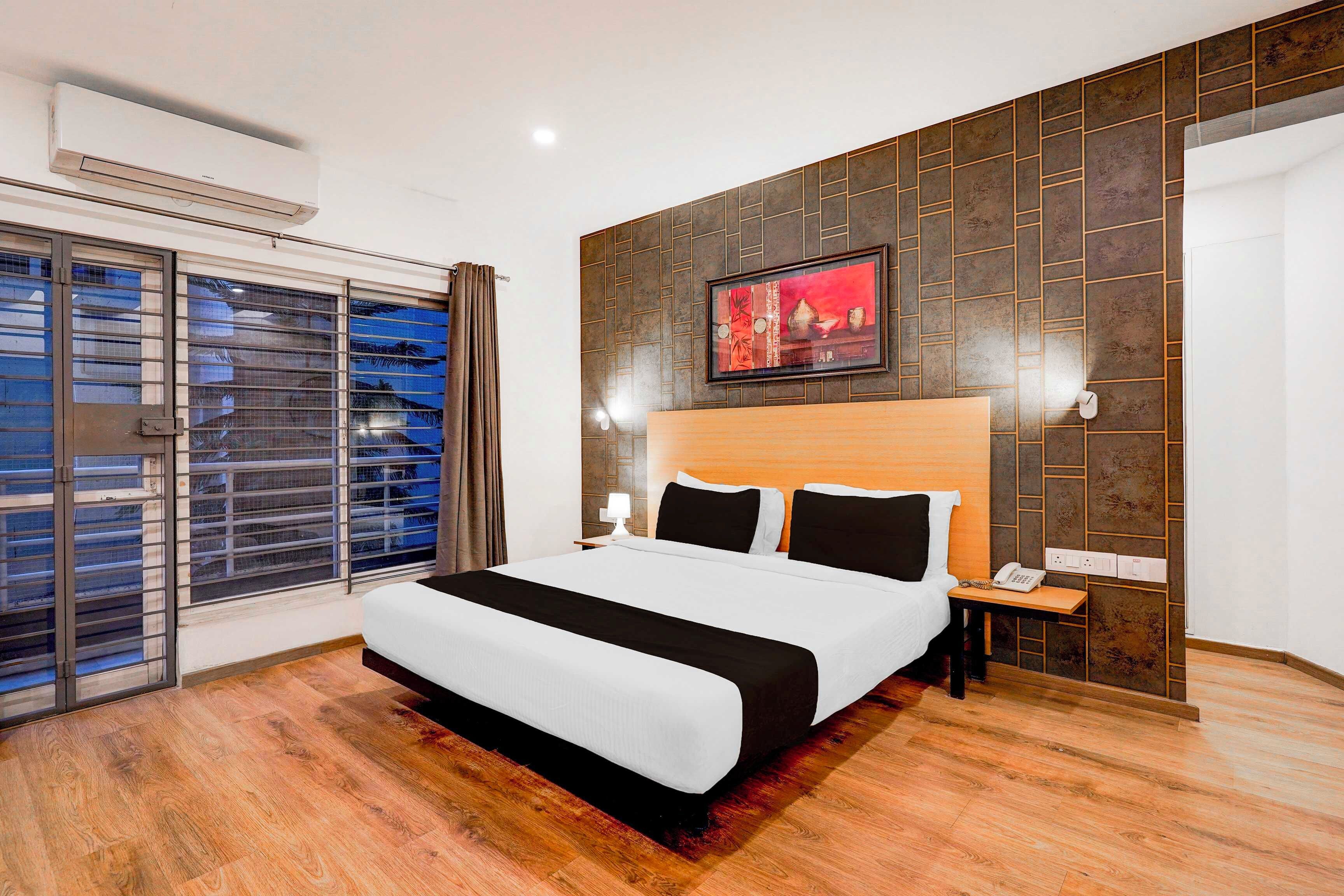 A hotel room with a large bed, a nightstand, a telephone, and a wall-mounted picture.