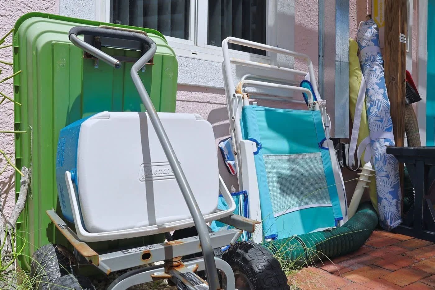 A cart with two large green containers and a blue and white folding chair.