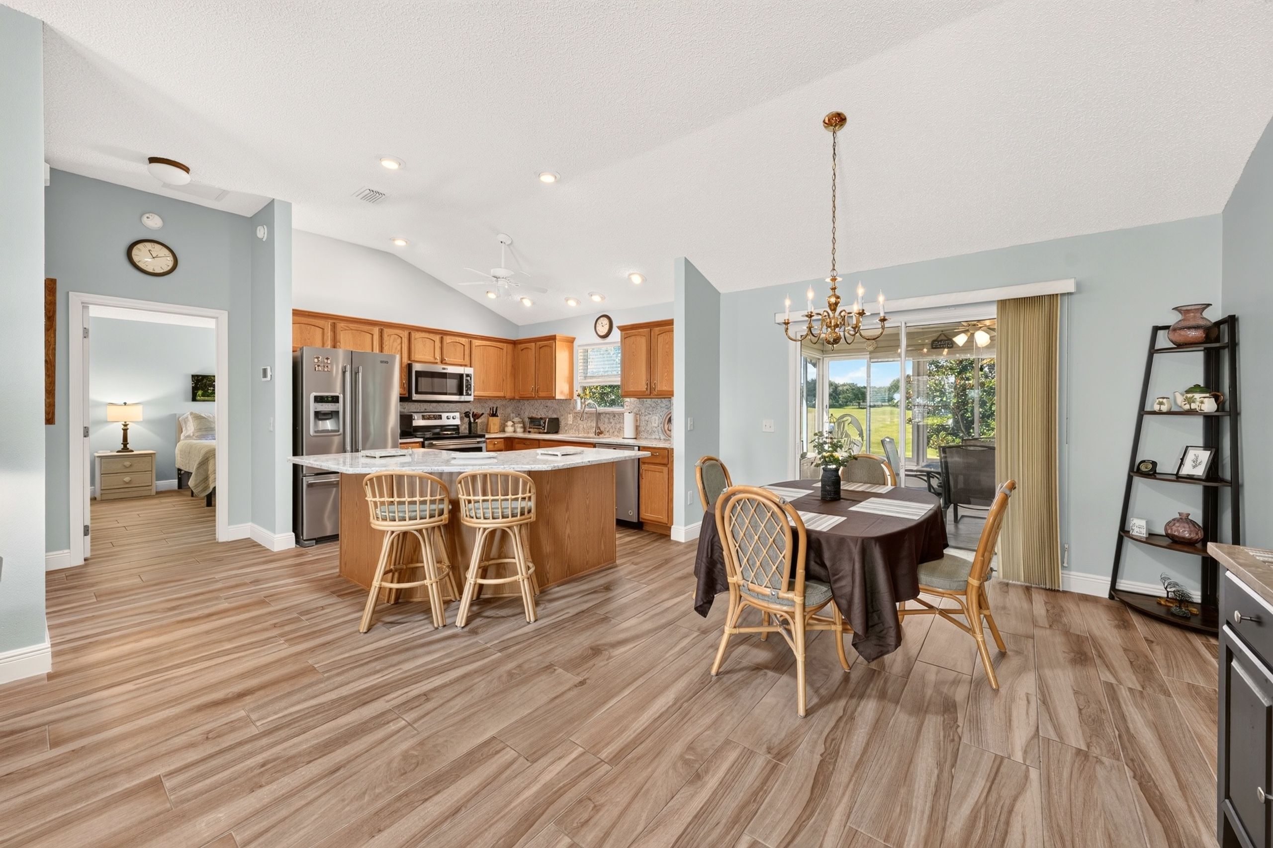 A spacious kitchen with wooden cabinets, a central island with bar stools, and a dining area with a chandelier.