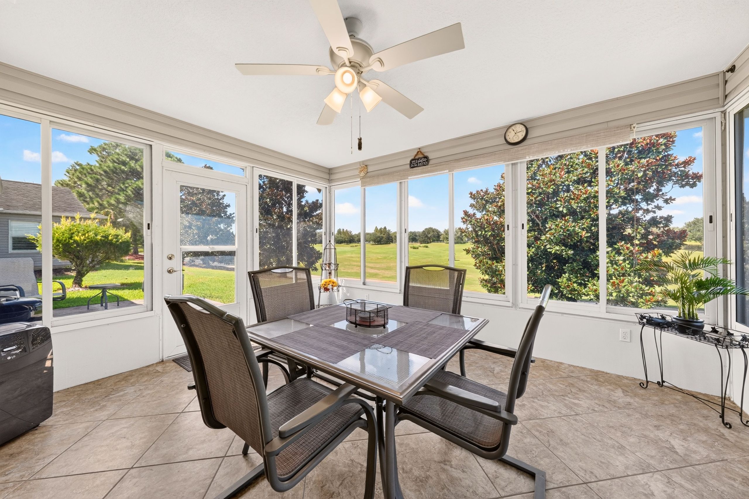 A sunroom with a table and chairs, large windows, and a ceiling fan.