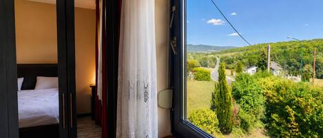 Un dormitorio con un ventanal grande, una cama y vistas a un paisaje verde.