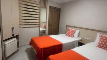 Habitación de hotel con dos camas, un armario, un espejo y una ventana con persianas.