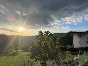 Ein Wohngebiet mit einem Haus, einem Garten und einer hügeligen Landschaft im Hintergrund.