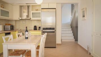 A modern kitchen with a built-in refrigerator, a dining table with chairs, and a staircase leading to an upper level.