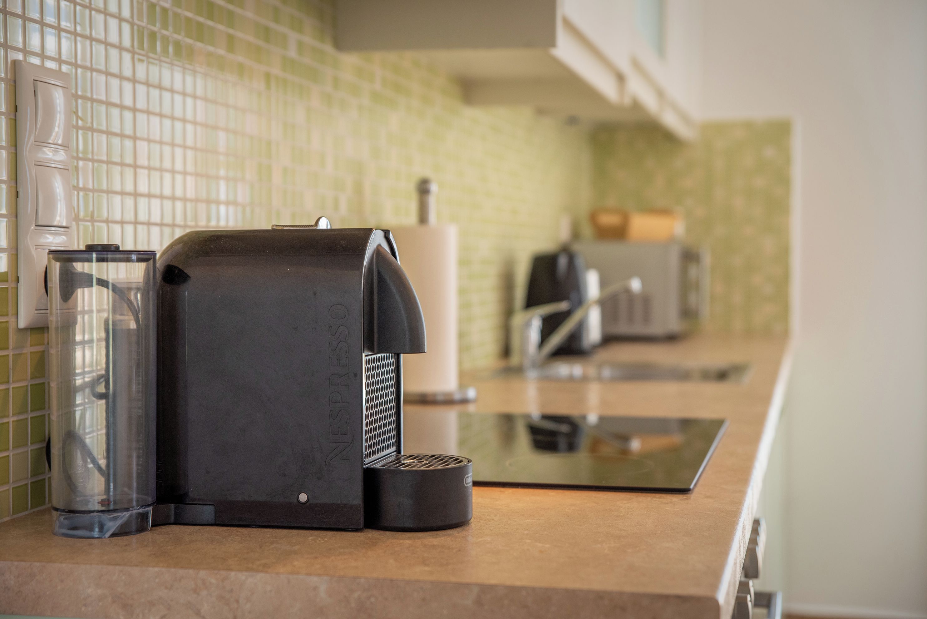 A kitchen with a Nespresso machine, a glass carafe, and a coffee maker on the counter.