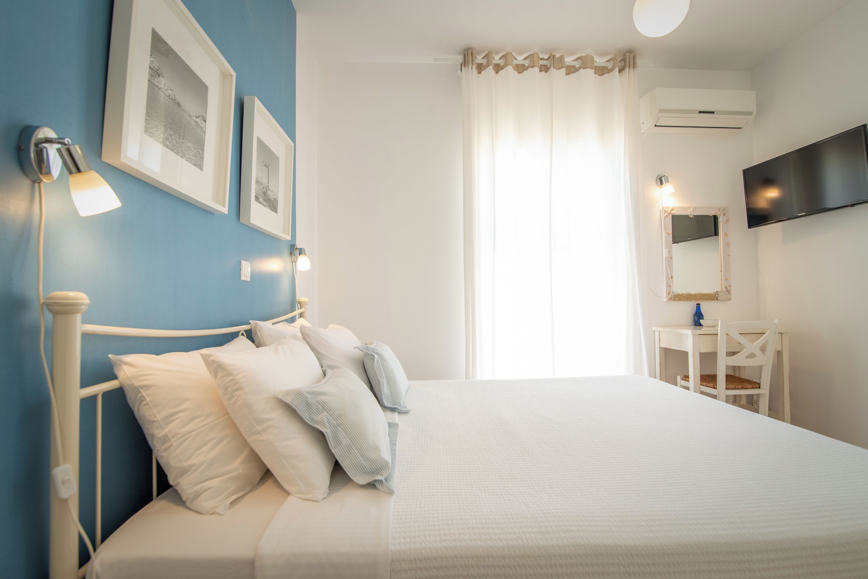 Un dormitorio con cama, lámparas de noche, televisor de pantalla plana, escritorio y una silla.