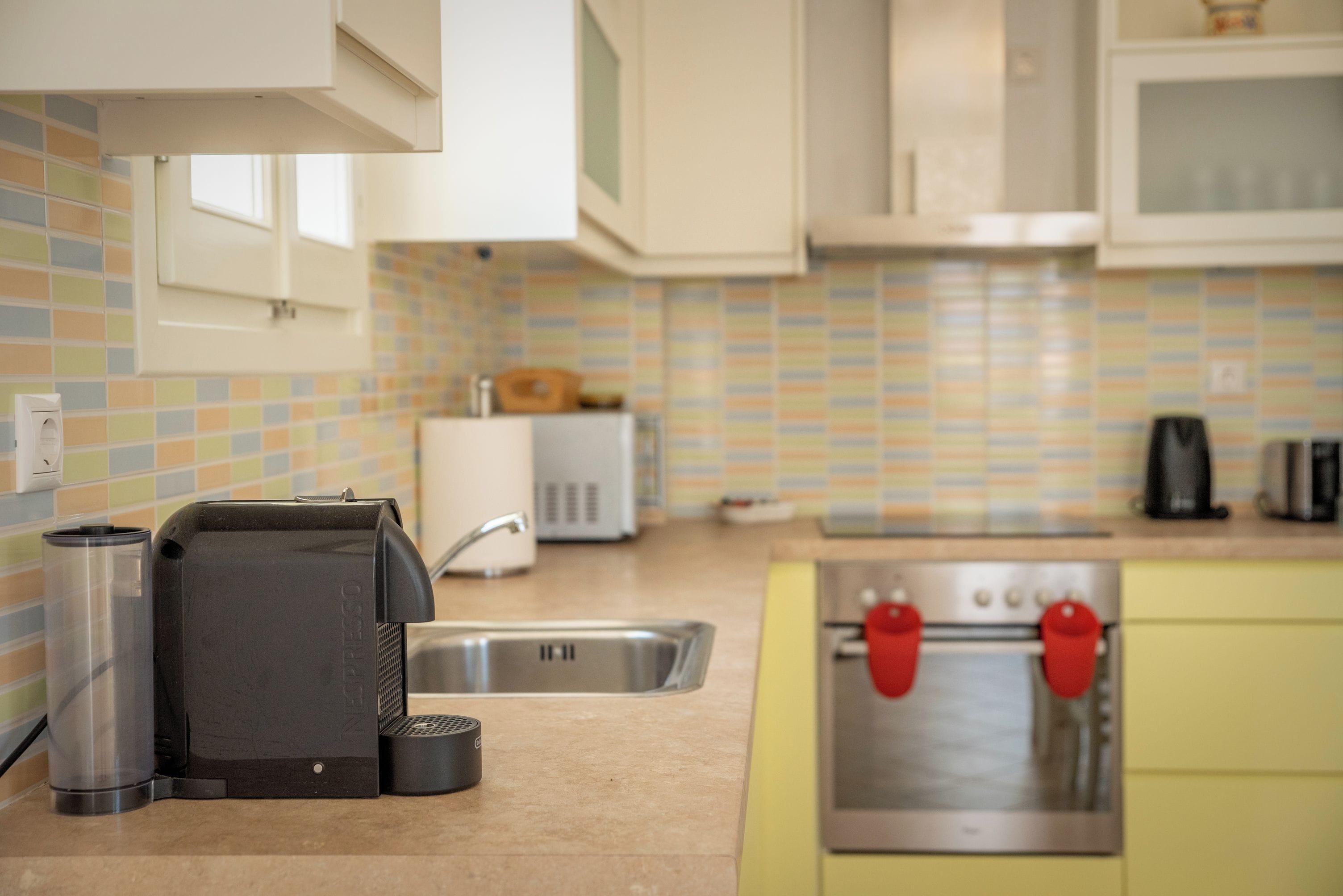 Una cocina equipada con cafetera, tostadora, lavabo y estufa.