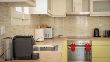 Una cocina equipada con cafetera, tostadora, lavabo y estufa.