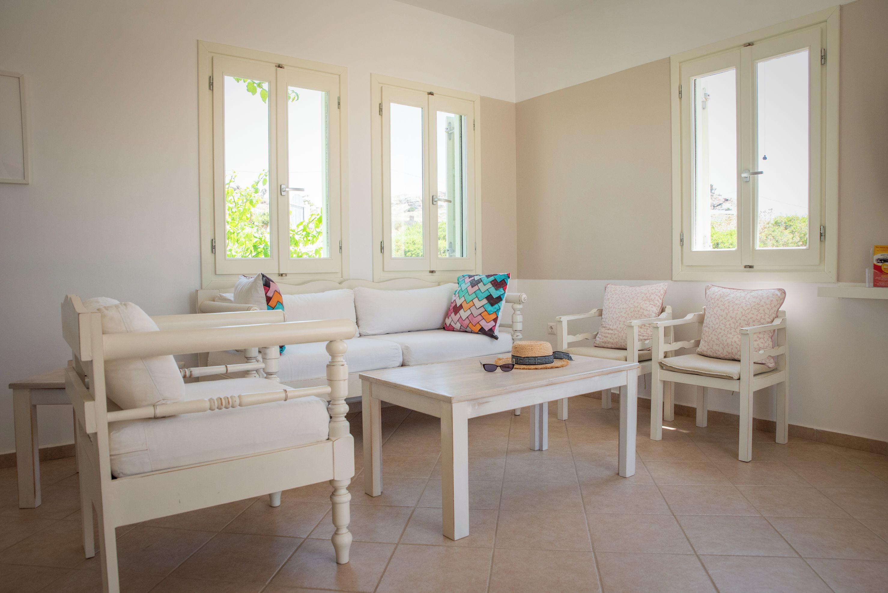 Una habitación con sofá, sillones, una mesa de centro y una ventana con vista a follaje.